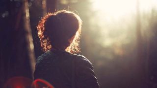 Mujer contempla el amanecer en paz en medio del bosque