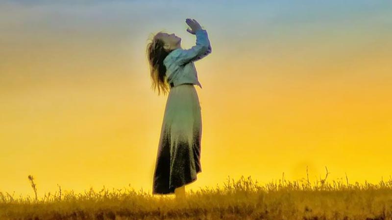 mujer orando a Dios de pie al aire libre