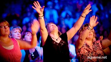 Mujeres cristianas adoran a Dios con manos alzadas en una reunion